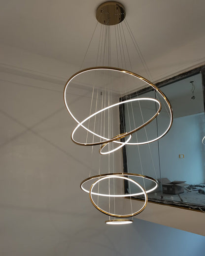 Seven-ring gold chandelier illuminating a newly finished stair void, creating an immediate focal point with minimal visual mass.