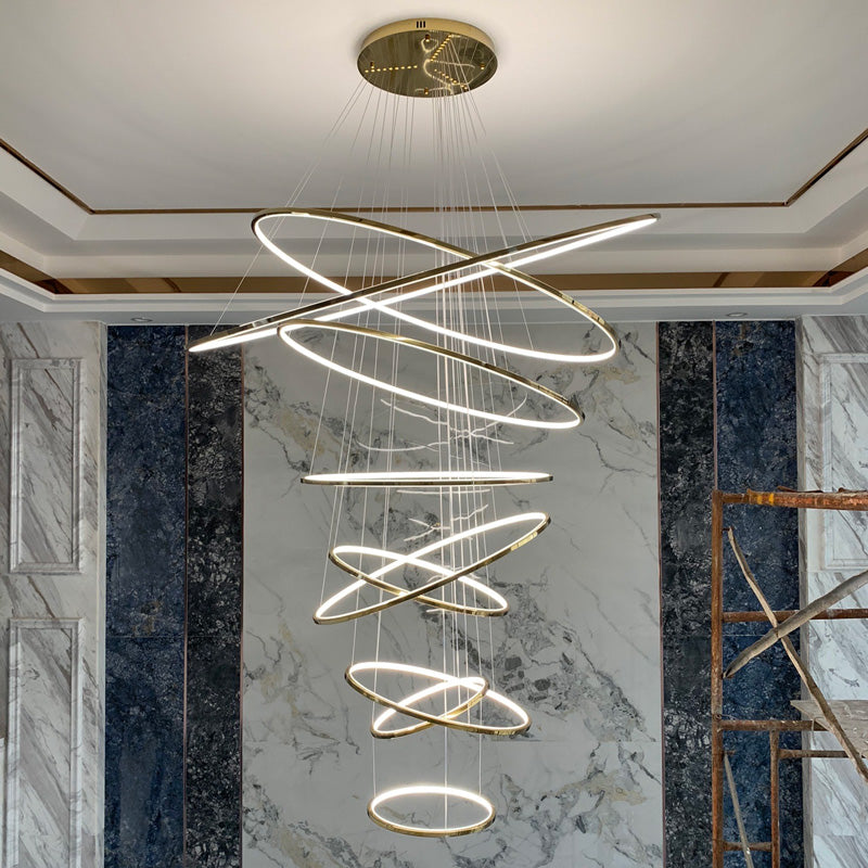 Nine-ring gold entryway chandelier against a marble wall, delivering a dense sculptural cascade for especially tall interiors.