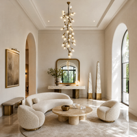 A modern chandelier with an antique brass metal vine frame and glowing glass buds hanging in a bright room.