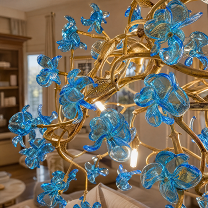 A modern chandelier with an intricate gold branch frame and handcrafted blue glass floral accents.