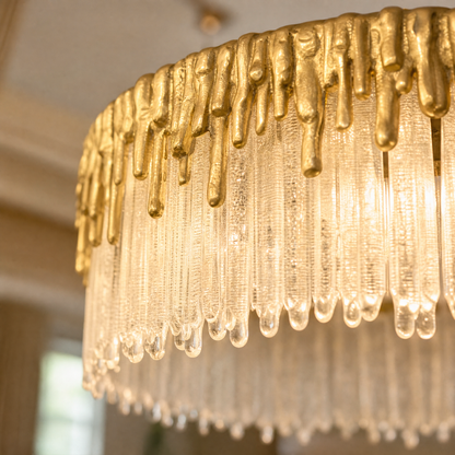 A double-tier chandelier with icicle-style textured crystal drops and a satin warm gold metal band.