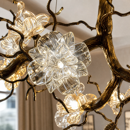 An antique brass chandelier with branching arms and frosted glass blossom shades suspended by cables.