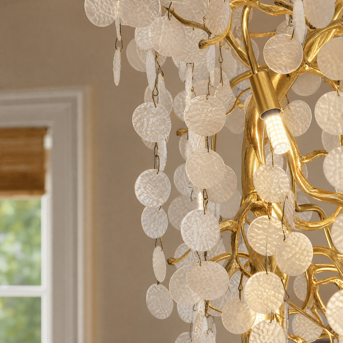 A multi-tiered cascading crystal chandelier with a gold frame hangs in a grand foyer with a curved staircase.