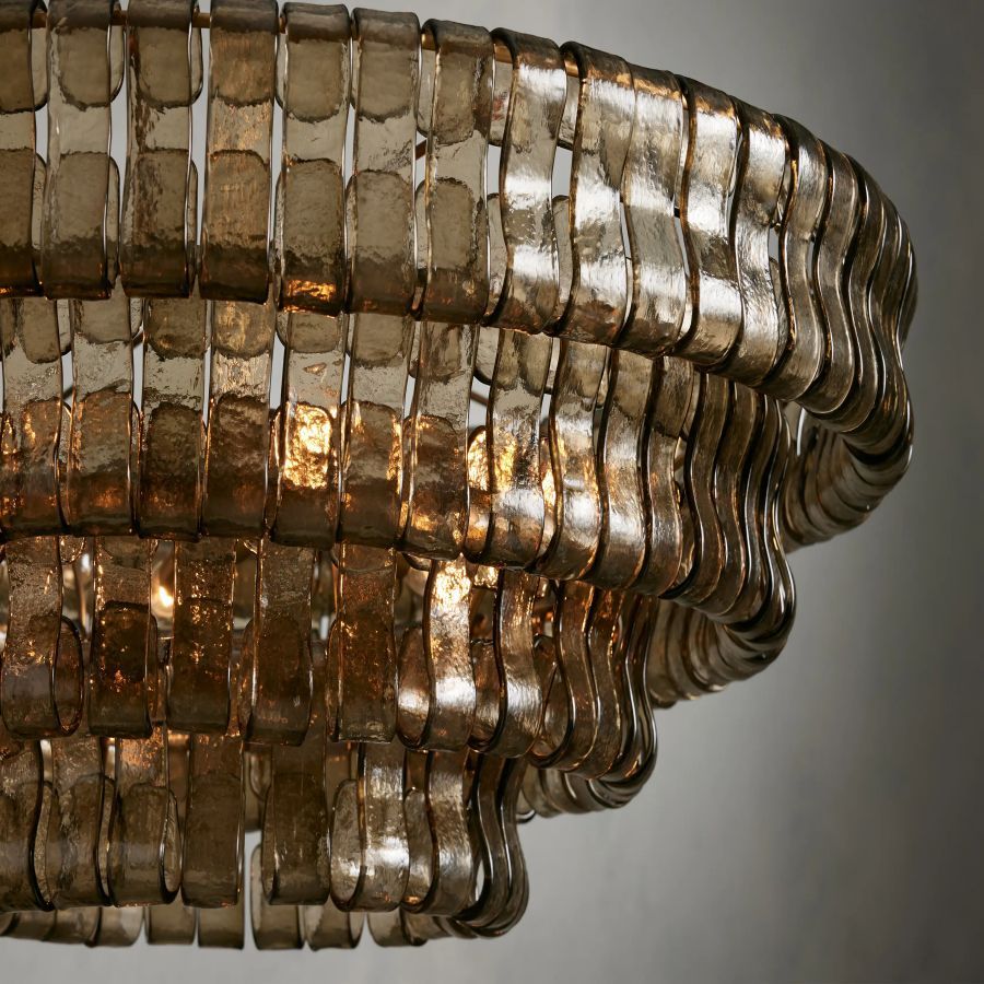 Givrelle round chandelier close-up of amber glass shades glowing on the brass frame